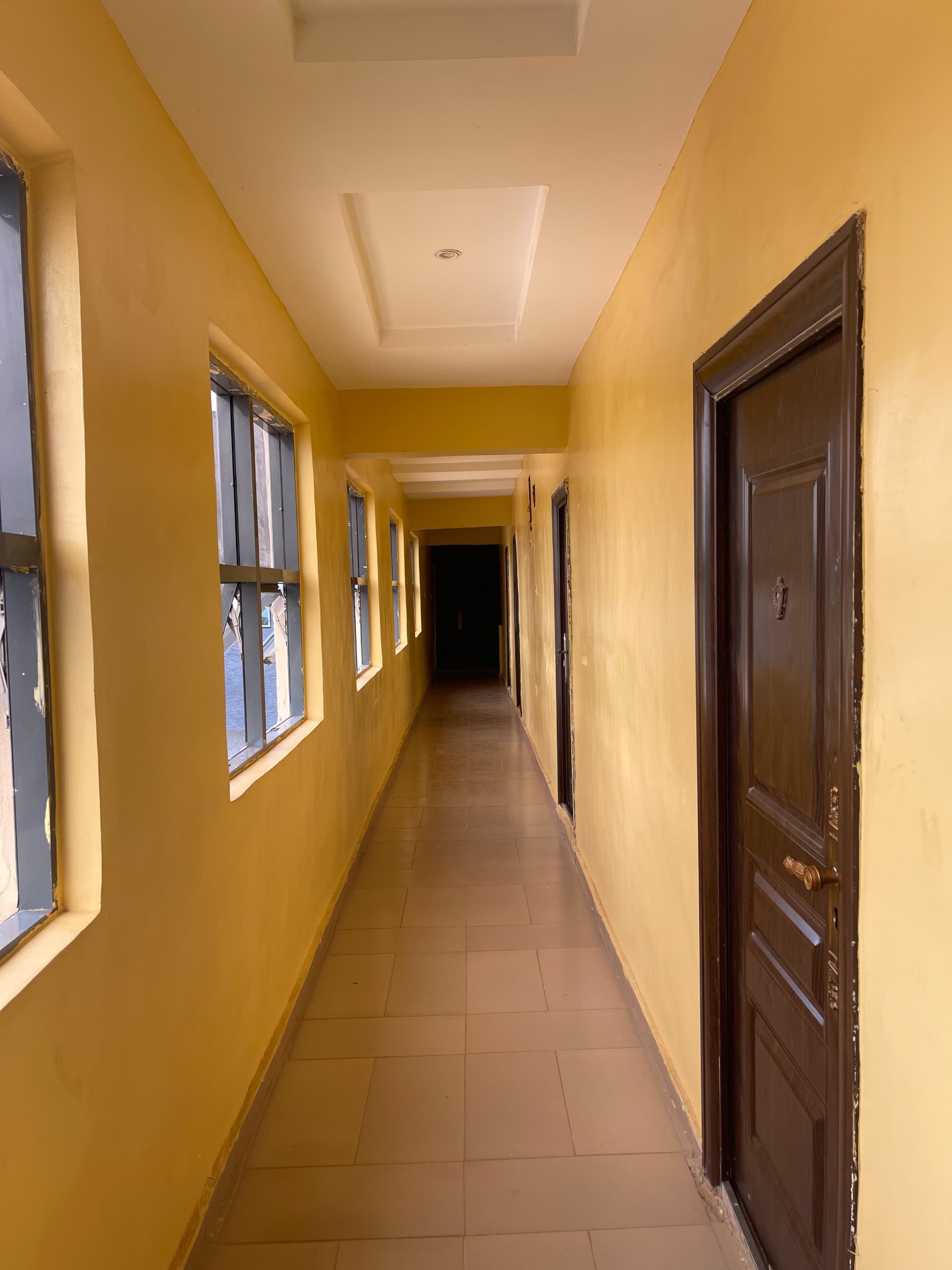 Interior hotel guest corridor with tiled floors and room access doors