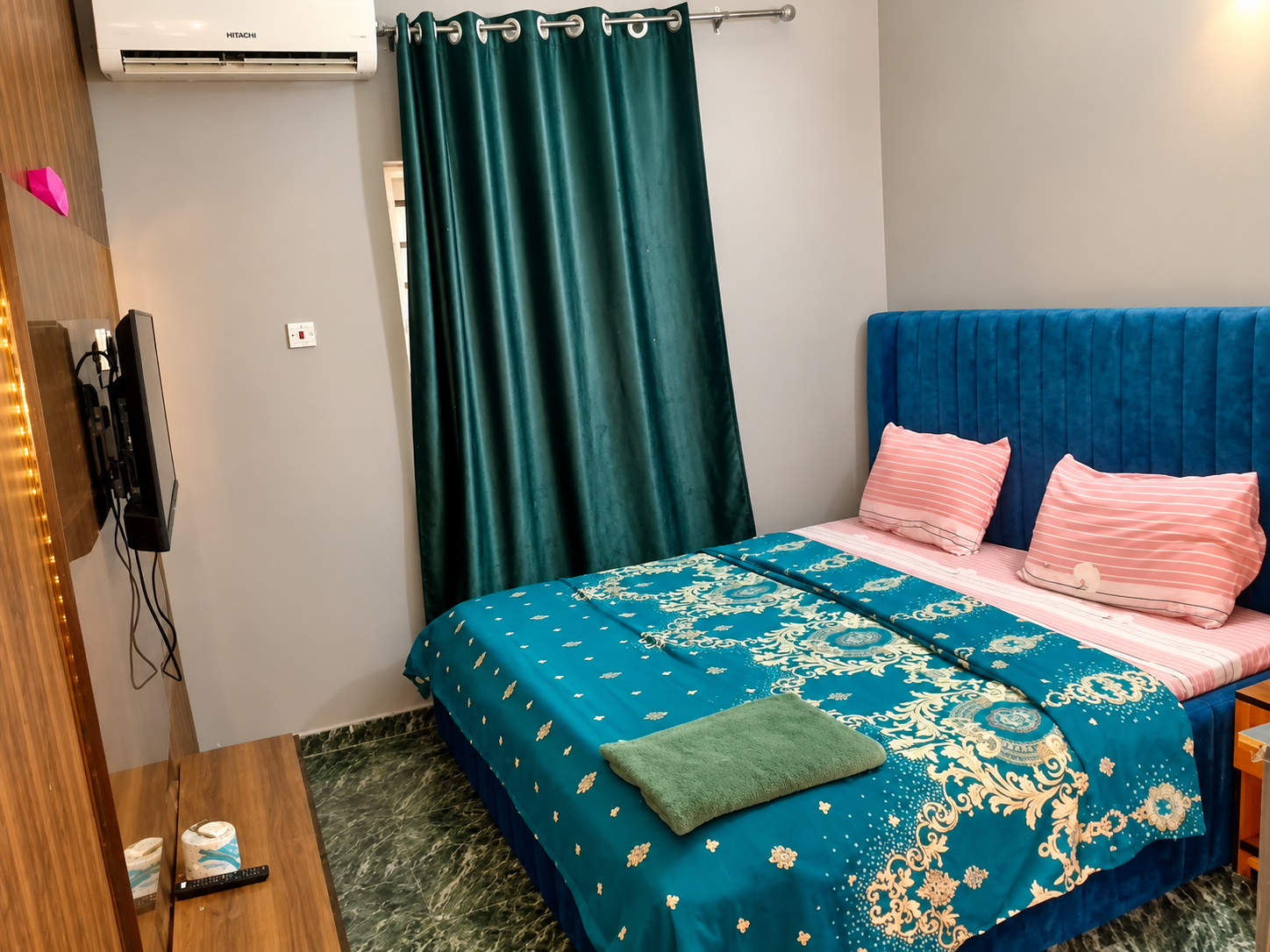 Executive room with blue velvet headboard, teal damask bedding, air conditioning, and wall-mounted TV