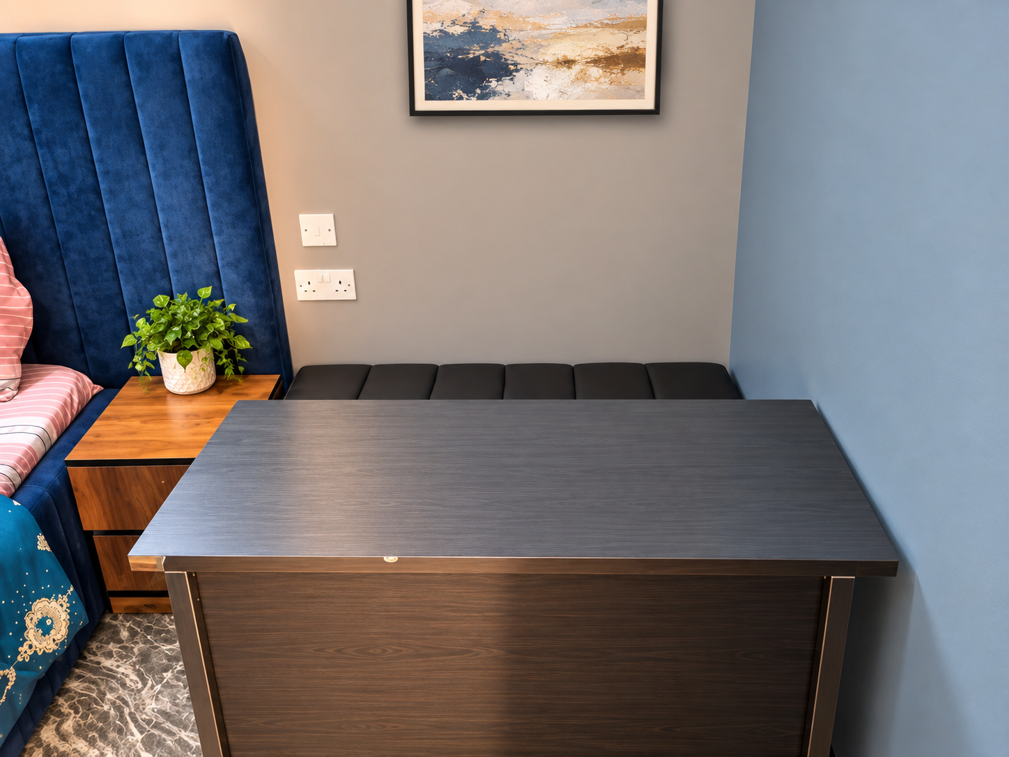 Executive room workspace with dark wood desk, padded bench seating, and abstract wall art