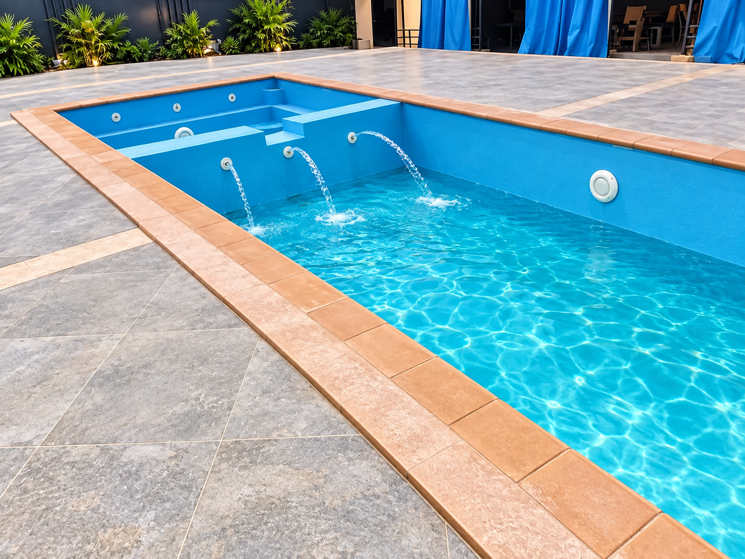 Angled view of the swimming pool with fountain jets and grey tiled poolside deck