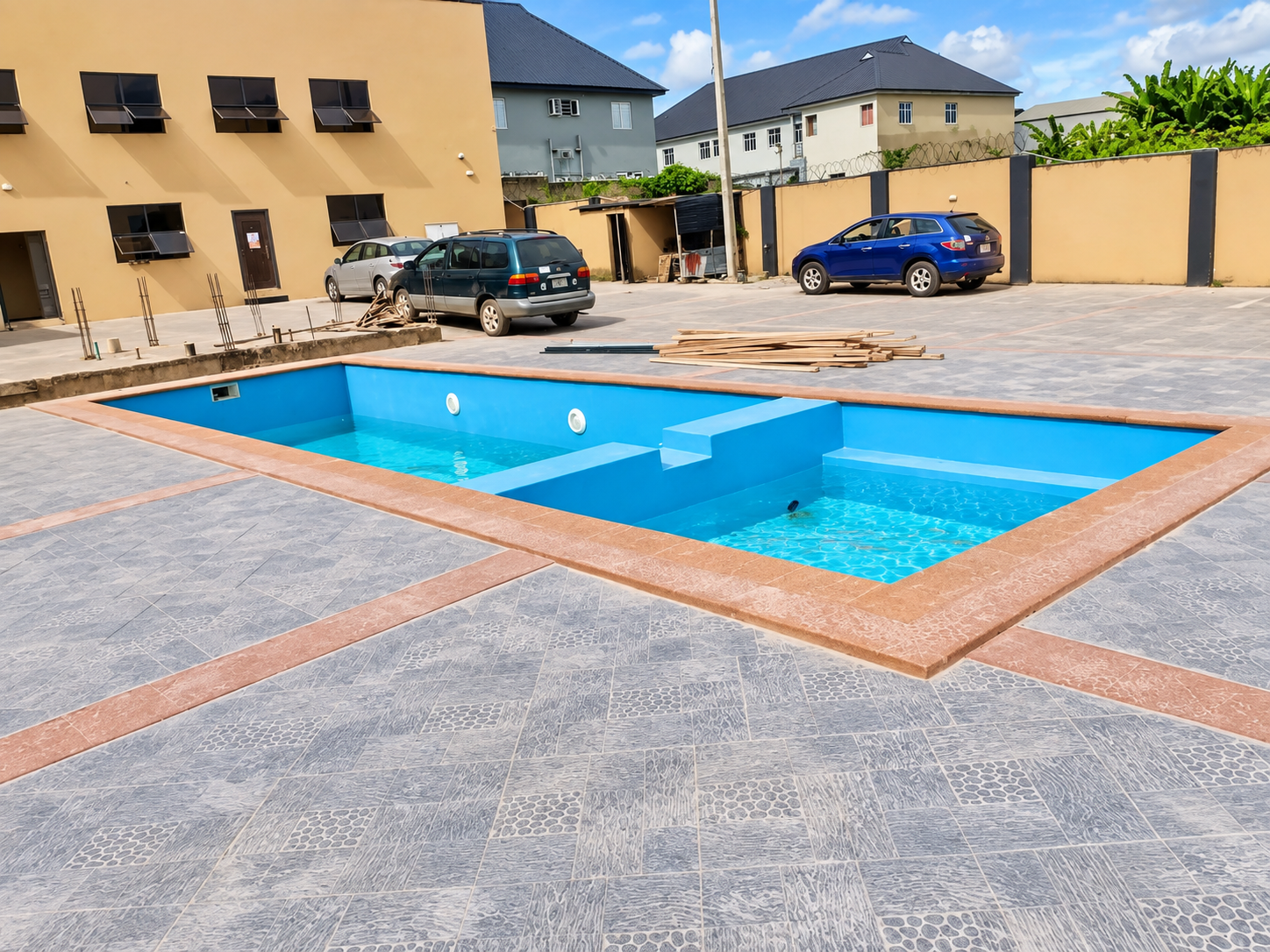 Swimming pool set within the hotel courtyard with building and parking visible